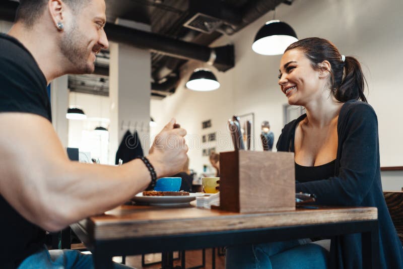 Junge Paare, die im Café am Datum, an trinkendem Kaffee sitzen und Nachtisch essen stockfotos
