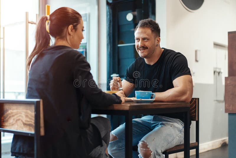 Junge Paare, die im Café am Datum, an trinkendem Kaffee sitzen und Nachtisch essen lizenzfreies stockbild