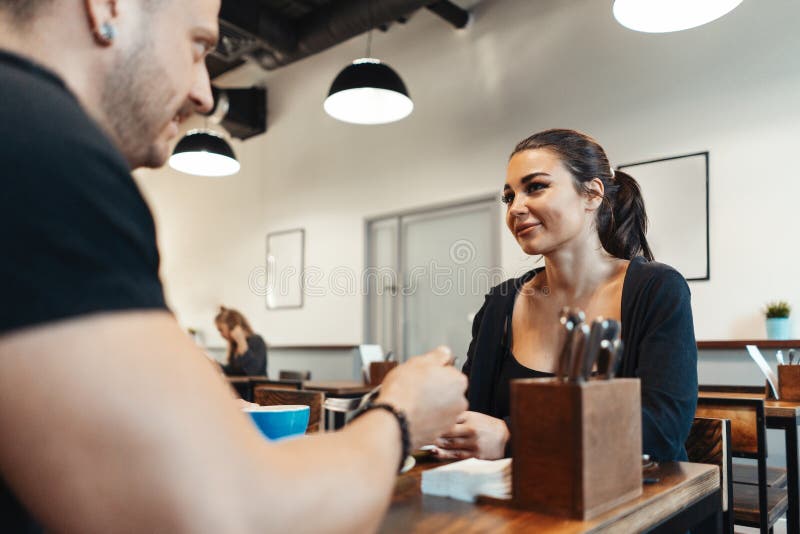 Junge Paare, die im Café am Datum, an trinkendem Kaffee sitzen und Nachtisch essen stockbild