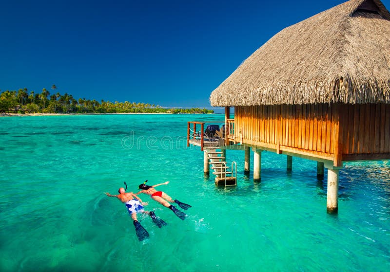 Junge Paare, die von der Hütte über tropischer Lagune snorkling sind lizenzfreie stockbilder Junge Paare, die von der Hütte über tropischer Lagune snorkling sind lizenzfreie stockbilder