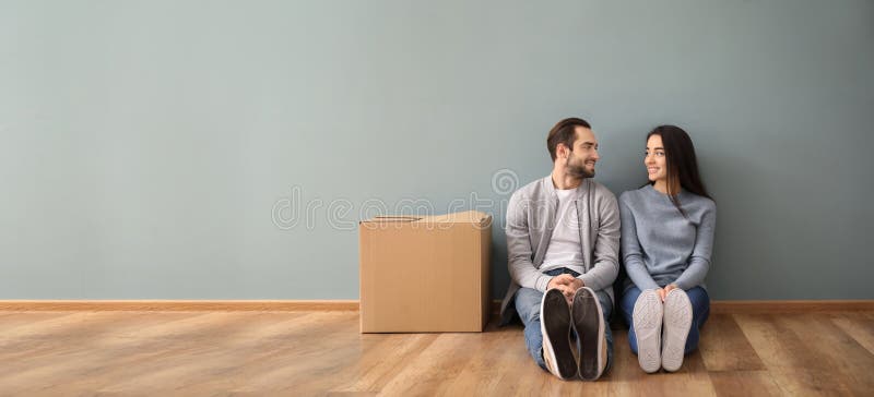 Junge Paare, die zuhause auf Boden nahe Kasten sitzen Bewegen in neues Haus stockbilder