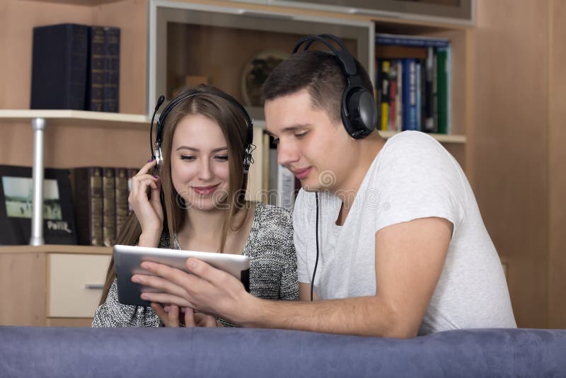 Junge Paare mit elektronischem Gerät lizenzfreies stockbild Junge Paare mit elektronischem Gerät lizenzfreies stockbild
