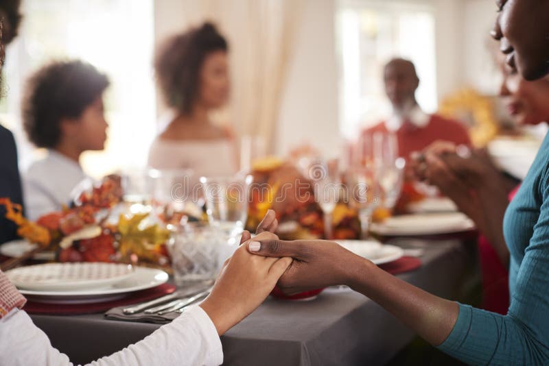 Junge schwarze erwachsene Frau und ihr Tochterhändchenhalten und Anmut mit ihrer multi Generationsfamilie am Danksagungslärm sage stockfoto Junge schwarze erwachsene Frau und ihr Tochterhändchenhalten und Anmut mit ihrer multi Generationsfamilie am Danksagungslärm sage stockfoto
