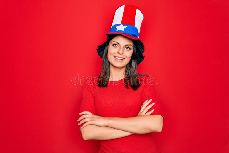 Junge schöne brunette Frau in geeinten Staaten, die feiern Unabhängigkeitstag glückliche Gesicht lächelnd mit gekreuzten Armen aus stockbild