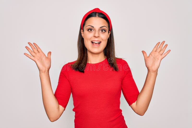 Junge schöne brunette Frau mit lockerem Hemd und Diadem über weißem Hintergrund feiert verrückt und erstaunt für Erfolg stockfotos