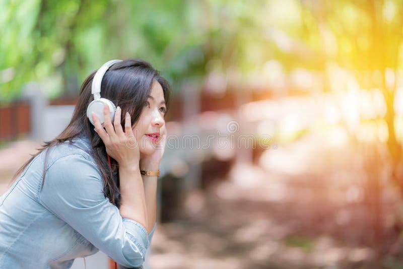 Young beautiful woman enjoying music in the garden listening to music with headphones. Young beautiful woman enjoying music in the garden listening to music with headphones.