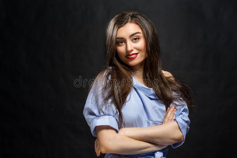Junge schöne lächelnde Frau streifte das blaue und weiße Smokinghemd, das über schwarzem Hintergrund aufwirft lizenzfreies stockbild Junge schöne lächelnde Frau streifte das blaue und weiße Smokinghemd, das über schwarzem Hintergrund aufwirft lizenzfreies stockbild