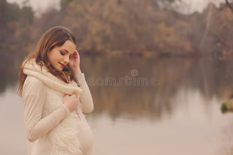 Junge schöne schwangere Frau auf gemütlichem wärmen Weg auf Herbstflußufer, warmes getont, Weichzeichnung stockbild Junge schöne schwangere Frau auf gemütlichem wärmen Weg auf Herbstflußufer, warmes getont, Weichzeichnung stockbild