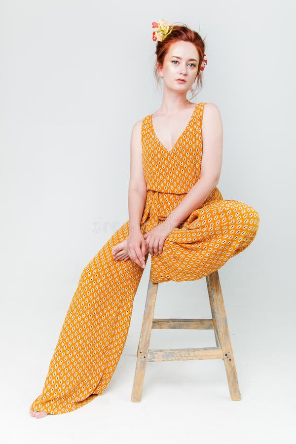 Junge Schönheit hat rotes Haar, das kreatives Gold aufwerfen in einem Studio mit Blumen bilden lizenzfreie stockfotos Junge Schönheit hat rotes Haar, das kreatives Gold aufwerfen in einem Studio mit Blumen bilden lizenzfreie stockfotos