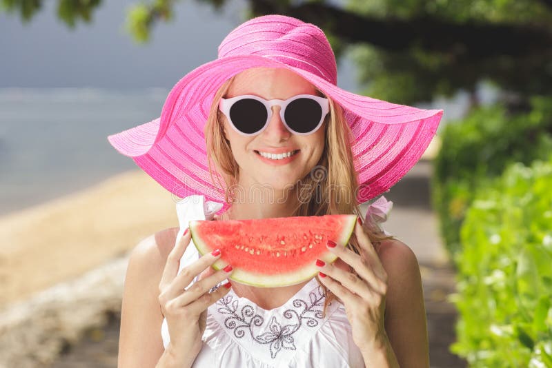 Junge Schönheit mit der Wassermelone, die rosa sunhat und SU trägt