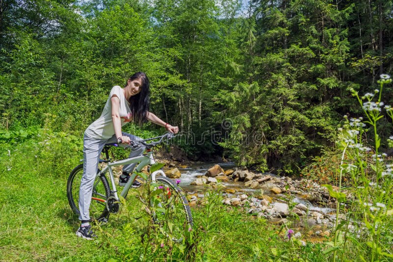 Junge, Schönheit sitzen auf einem Fahrrad, gegen den Hintergrund von einem Gebirgsfluss lizenzfreies stockfoto Junge, Schönheit sitzen auf einem Fahrrad, gegen den Hintergrund von einem Gebirgsfluss lizenzfreies stockfoto