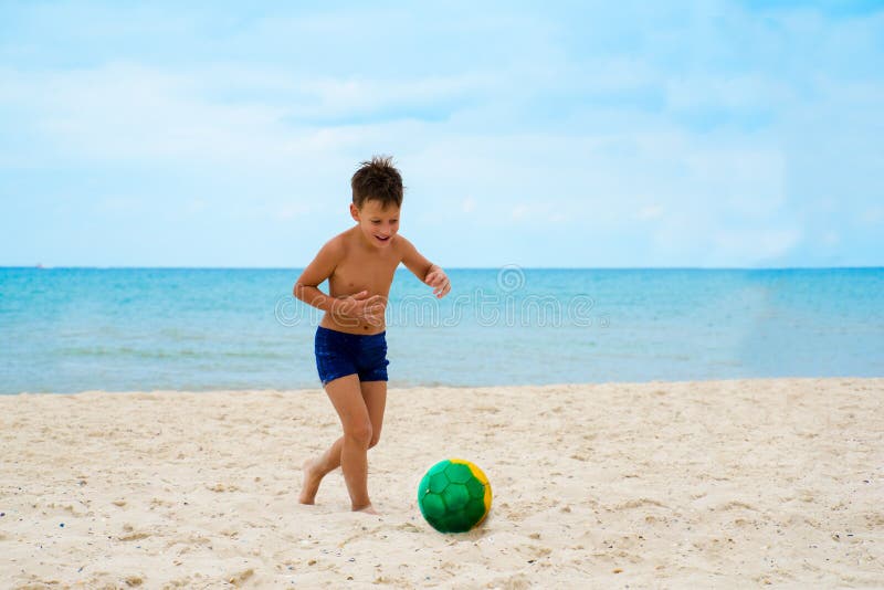 Junge spielt Fußball auf Strand stockfotografie Junge spielt Fußball auf Strand stockfotografie