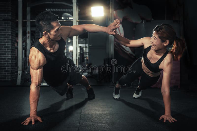 Young sporty couple working out together at gym, Fitness men and women giving each other a high five after the training session in gym. Young sporty couple working out together at gym, Fitness men and women giving each other a high five after the training session in gym.