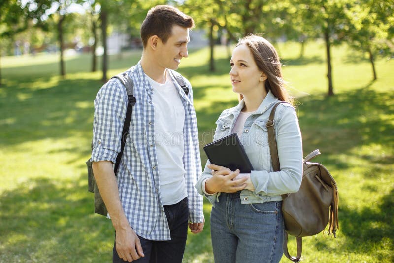 Junge Studentenpaare, die in den Park und in der Unterhaltung gehen stockfoto Junge Studentenpaare, die in den Park und in der Unterhaltung gehen stockfoto