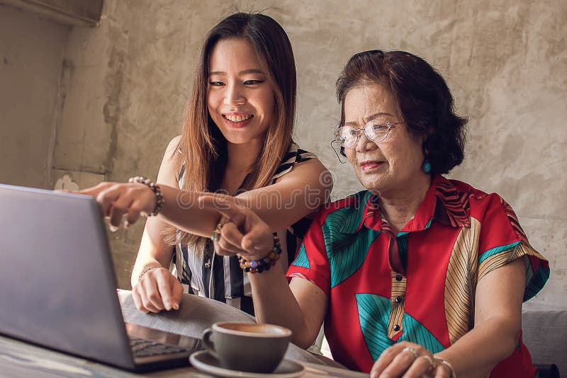 Junge und Alte asiatische Frauen verwenden Laptop zusammen