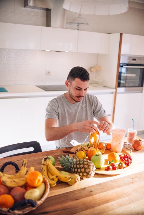 Young and healthy man putting fruits in his blender early in the morning. Young and healthy man putting fruits in his blender early in the morning