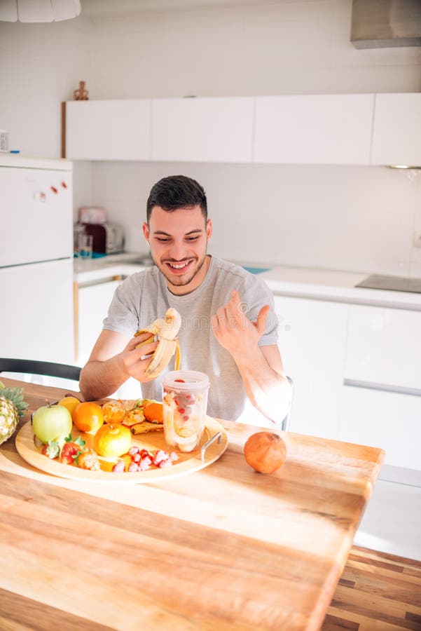 Young and healthy man putting fruits in his blender early in the morning. Young and healthy man putting fruits in his blender early in the morning