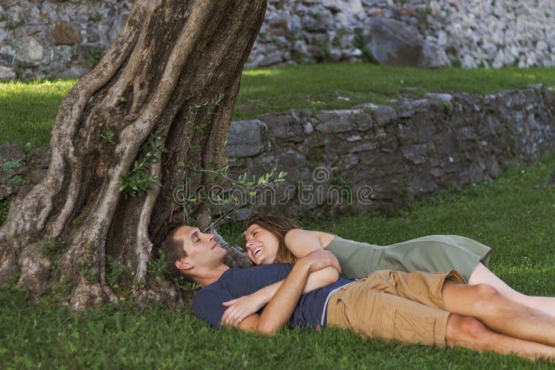 Junge verbinden in der Liebe, die unter einem Baum in einem Schloss sitzt lizenzfreie stockfotografie Junge verbinden in der Liebe, die unter einem Baum in einem Schloss sitzt lizenzfreie stockfotografie