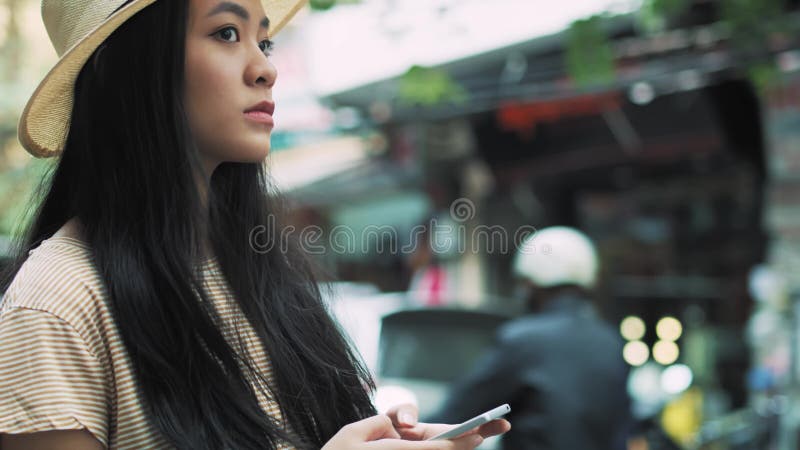 Junge vietnamesische Frau, die in der Stadt Smartphone benutzt