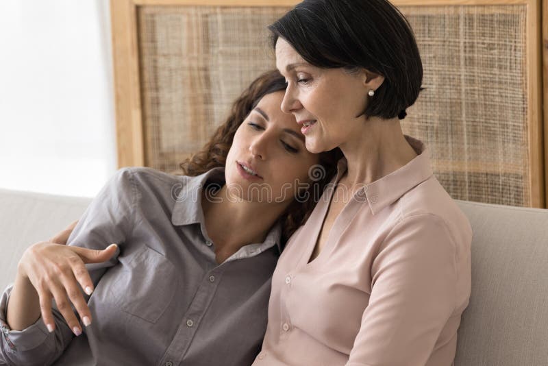 Junge weibliche Tochter findet emotionale Unterstützung in fürsorglichen Mutterumarmungen stockbild