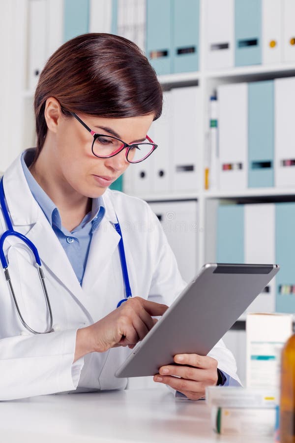Junge Ärztin unter Verwendung des Tablet-Computers stockbild Junge Ärztin unter Verwendung des Tablet-Computers stockbild