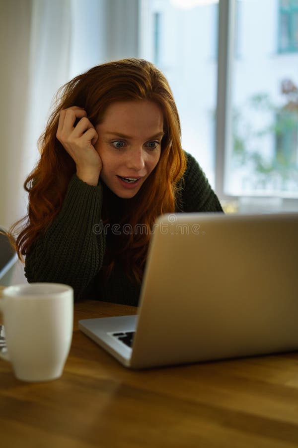 Junge überraschte Frau, die vor Laptop sitzt stockbild Junge überraschte Frau, die vor Laptop sitzt stockbild