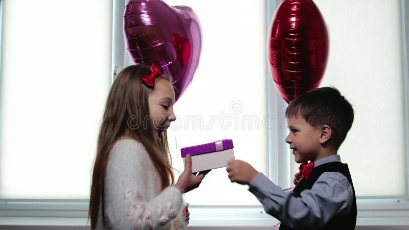 Jungenhände ein Feld mit einem Geschenk zu einem Mädchen auf dem Hintergrund von Ballons