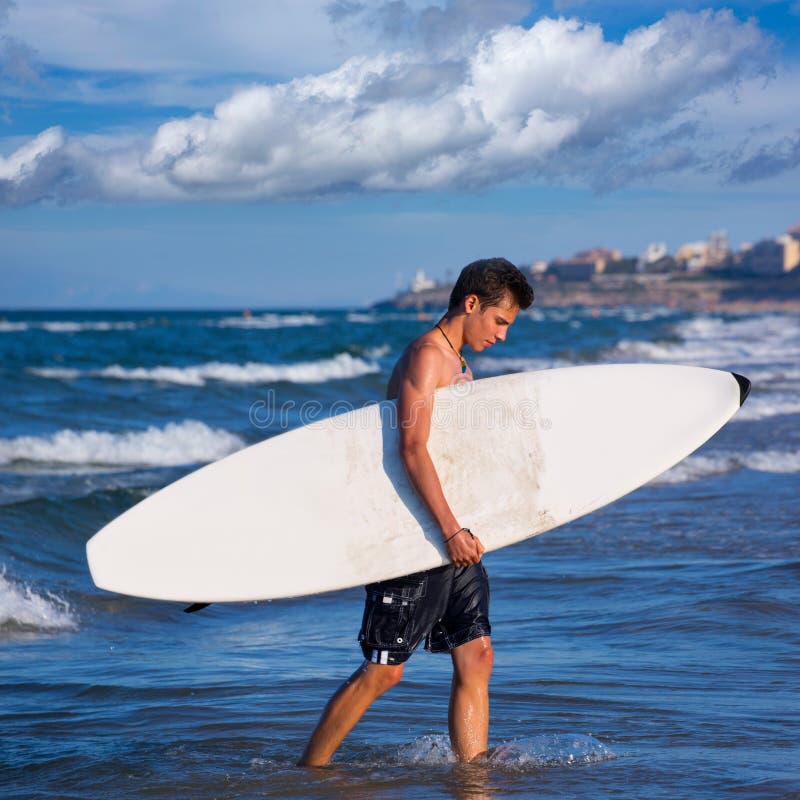 Boy handsome surfer holding surfboard coming out from the waves. Boy handsome surfer holding surfboard coming out from the waves