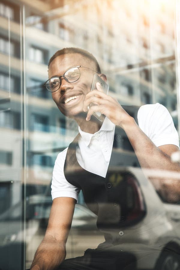 Junger AfroamerikanerGeschäftsmann in der Klage und Brillen, die am Telefon auf dem Hintergrund des Geschäftszentrums sprechen stockbilder Junger AfroamerikanerGeschäftsmann in der Klage und Brillen, die am Telefon auf dem Hintergrund des Geschäftszentrums sprechen stockbilder