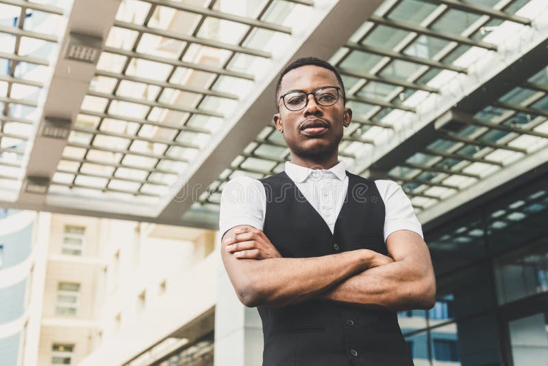 Junger AfroamerikanerGeschäftsmann in der Klage und Brillen, die am Telefon auf dem Hintergrund des Geschäftszentrums sprechen stockfotografie Junger AfroamerikanerGeschäftsmann in der Klage und Brillen, die am Telefon auf dem Hintergrund des Geschäftszentrums sprechen stockfotografie
