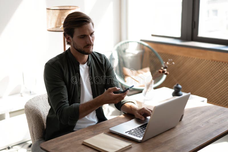 Junger Arbeitnehmer am Arbeitsplatz, der über das Mobiltelefon die sozialen Medien auf dem Smartphone abfragt und dabei den Schrei stockbilder