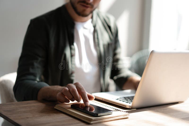 Junger Arbeitnehmer am Arbeitsplatz, der über das Mobiltelefon die sozialen Medien auf dem Smartphone abfragt und dabei den Schrei lizenzfreie stockfotografie