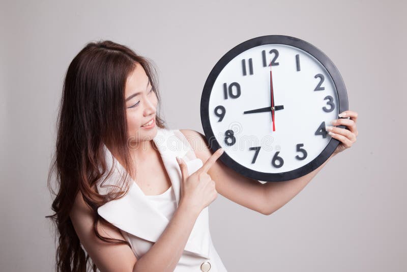 Junger Asiatinpunkt zu einer Uhr lizenzfreie stockbilder Junger Asiatinpunkt zu einer Uhr lizenzfreie stockbilder