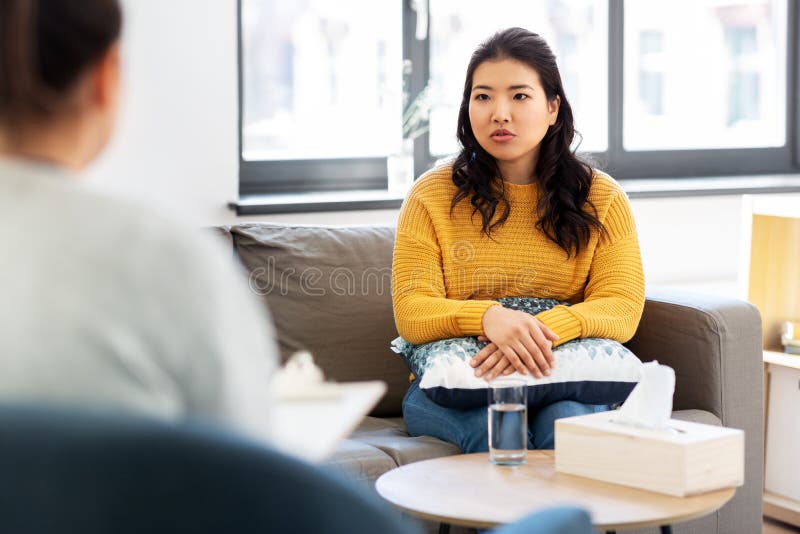 Psychology and mental therapy concept - young asian women patient and psychologist at psychotherapy session. Psychology and mental therapy concept - young asian women patient and psychologist at psychotherapy session