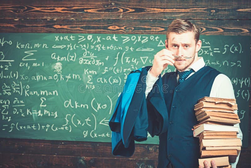 Junger blonder Professor, der auf seine Gläser sich setzt Intelligenter Mann im Klagenholdingstapel von Büchern lizenzfreies stockbild Junger blonder Professor, der auf seine Gläser sich setzt Intelligenter Mann im Klagenholdingstapel von Büchern lizenzfreies stockbild