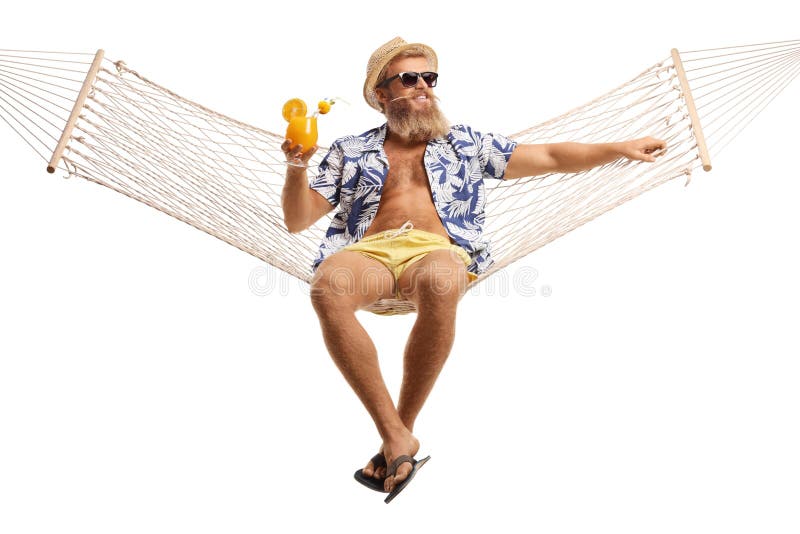 Junger bärtiger Kerl, der auf einem Hängemattennetz mit einem Cocktail sitzt lizenzfreie stockfotografie