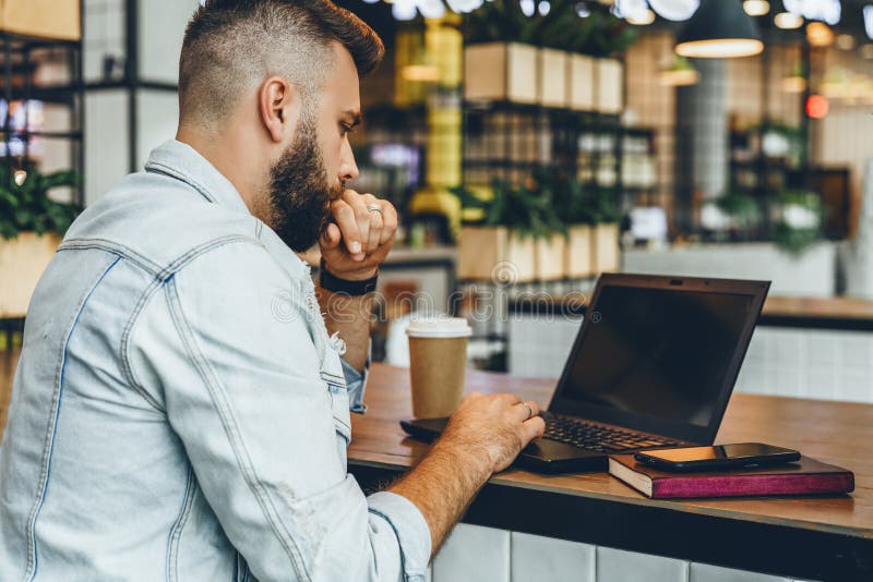 Junger bärtiger Mann sitzt im Café und schreibt auf Laptop Blogger arbeitet im Kaffeehaus Kerl überprüft die E-Mail auf Computer stockfoto Junger bärtiger Mann sitzt im Café und schreibt auf Laptop Blogger arbeitet im Kaffeehaus Kerl überprüft die E-Mail auf Computer stockfoto