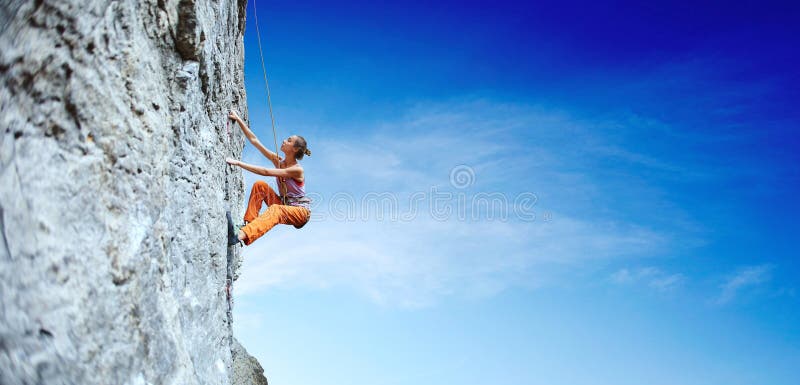 Junger dünner Frauenkletterer, der auf der Klippe klettert
