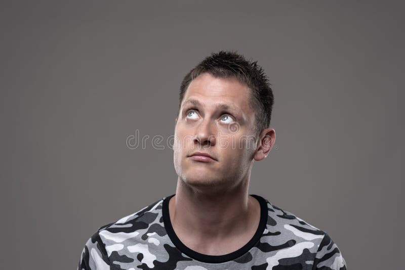 Junger erwachsener gut aussehender Mann, der oben durchdacht nach einer Lösung denkend sucht stockbild
