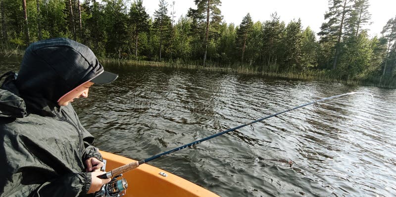 Junger Fischer fischt auf dem Boot in einem schwedischen See lizenzfreies stockbild