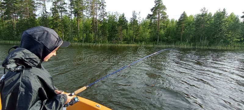 Junger Fischer fischt auf dem Boot in einem schwedischen See lizenzfreie stockfotografie