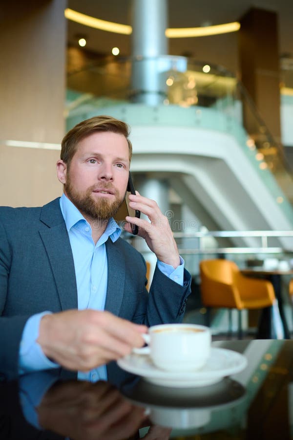 Junger Geschäftsmann mit Smartphone, der mit Partnern kommuniziert stockbild