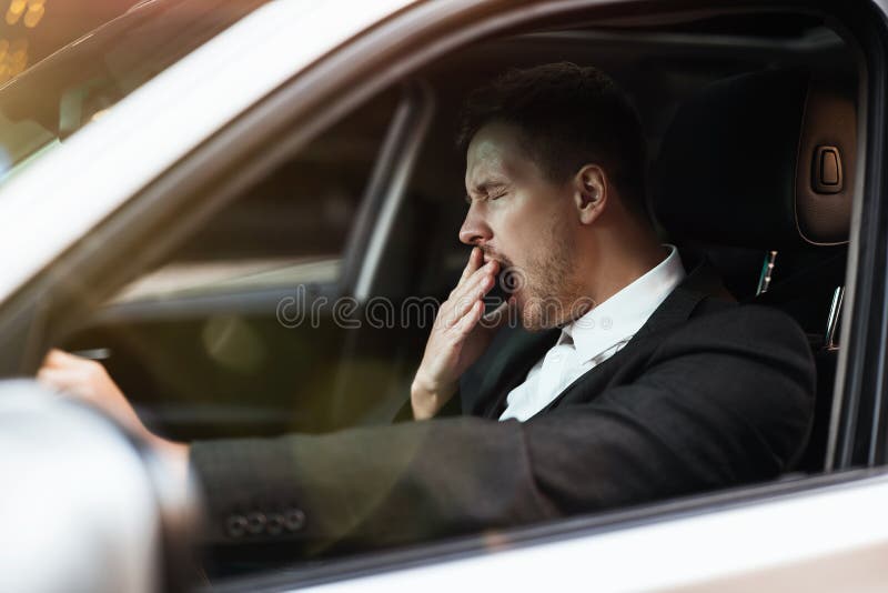 Junger Geschäftsmann sieht müde gähnende wann stationierend in seinem Auto mit Open Fenster, die Sicherheit, die Konzept wird stockbild