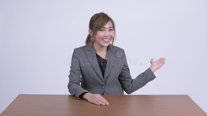 Junger glücklicher asiatischer Geschäftsfraugruß am Schreibtisch