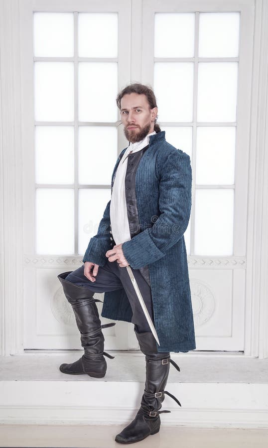Junger gutaussehender Mann in der mittelalterlichen Kleidung mit Klingenstellung lizenzfreies stockbild Junger gutaussehender Mann in der mittelalterlichen Kleidung mit Klingenstellung lizenzfreies stockbild