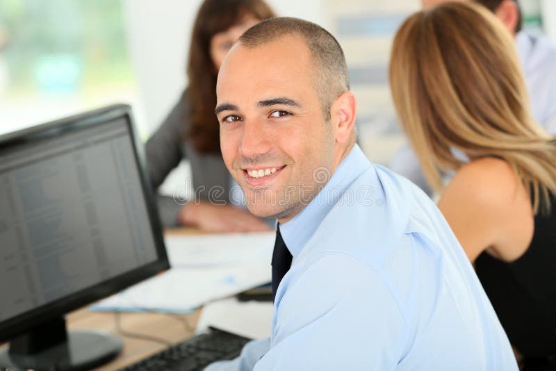 Junger lächelnder Geschäftsmann, der an Computer arbeitet lizenzfreie stockfotos Junger lächelnder Geschäftsmann, der an Computer arbeitet lizenzfreie stockfotos
