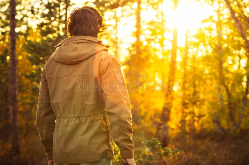 Junger Mann, der allein im Wald im Freien mit Sonnenuntergangnatur auf Hintergrund steht lizenzfreie stockbilder Junger Mann, der allein im Wald im Freien mit Sonnenuntergangnatur auf Hintergrund steht lizenzfreie stockbilder