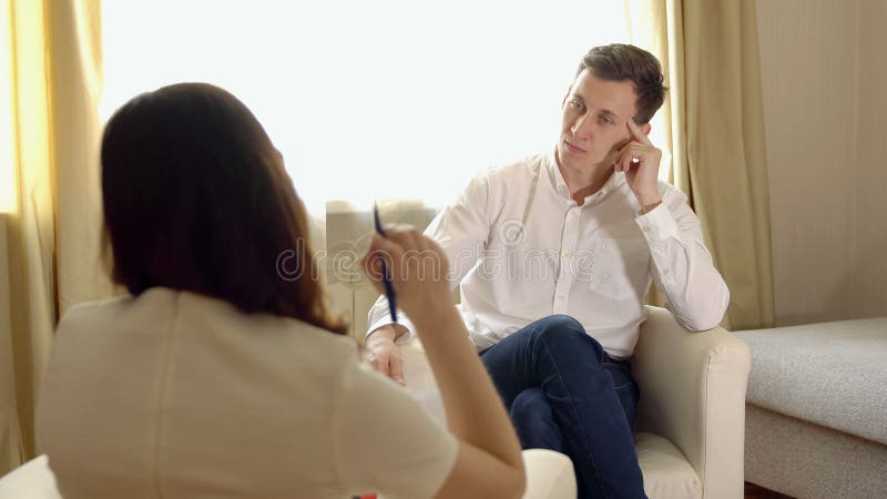 Junger Mann an der Aufnahme eines Frauenpsychologen lizenzfreies stockbild Junger Mann an der Aufnahme eines Frauenpsychologen lizenzfreies stockbild