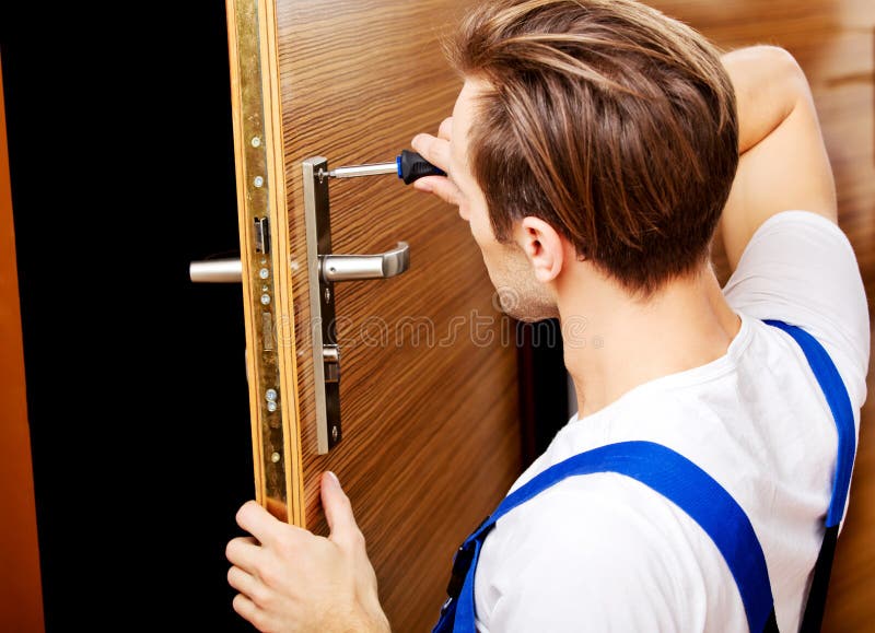 Junger Mann, der die Tür mit Schraubenzieher repariert