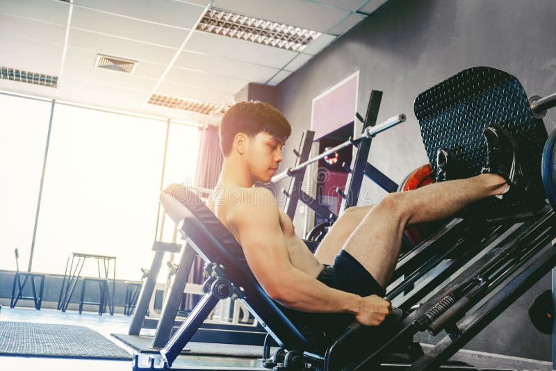 Junger Mann der Eignung, der unter Verwendung der Rudermaschine in der Turnhalle trainiert lizenzfreies stockbild Junger Mann der Eignung, der unter Verwendung der Rudermaschine in der Turnhalle trainiert lizenzfreies stockbild